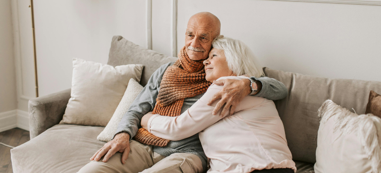 Elderly couple hugging on a couch, reflecting the care provided by senior movers Boston locals trust.