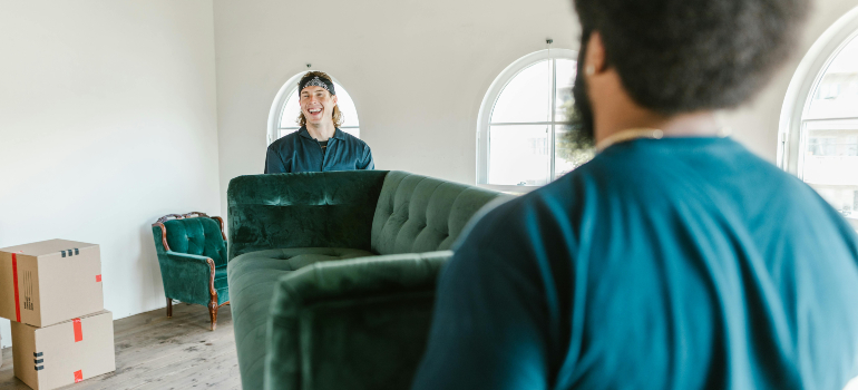 Movers carrying a green sofa, highlighting storage in Boston area.