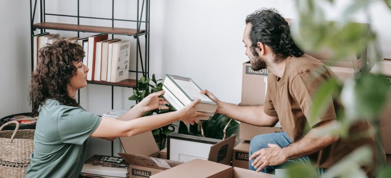 Couple Packing Books In A Box after reading Decluttering Tips Before Moving
