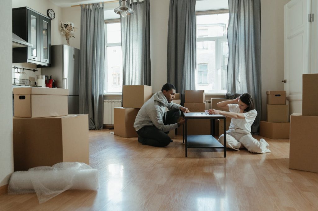 man and woman sitting on floor and waiting for furniture movers Boston MA