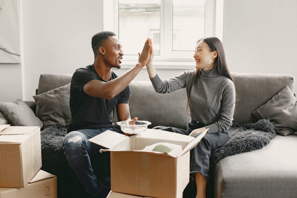 Man and Woman Sitting on Couch Unpacking Boxes after booking white glove delivery Boston