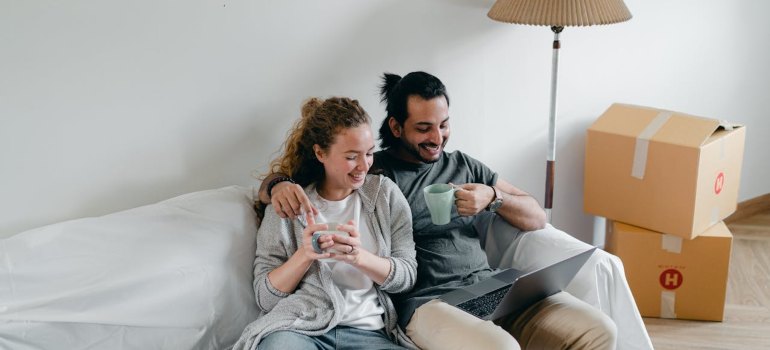Multiethnic couple embracing on couch while watching laptop at home