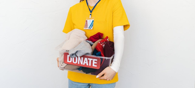 a girl holding a plastic box with some clothes in it 