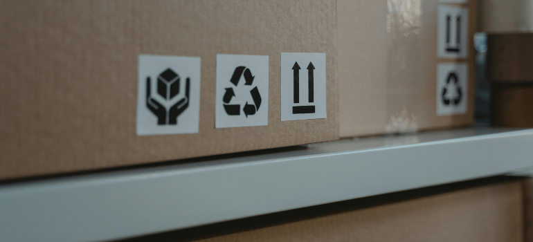 Cardboard box with eco-friendly symbols, including a recycling icon, highlighting green moving tips to lower your carbon footprint.