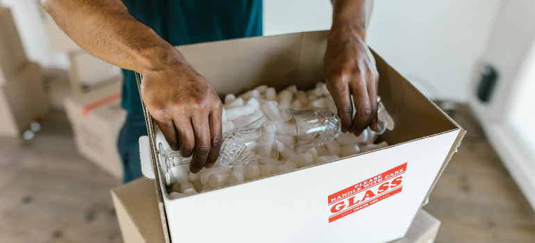 Packing a glass item with peanuts, showing how to pack fragile items safely.